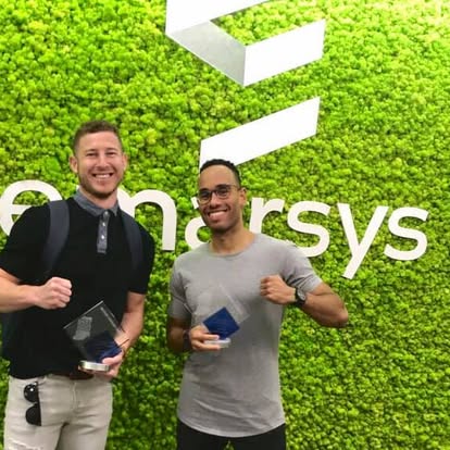 Michael Becker and Chris holding awards in front of Emarsys’ green living wall