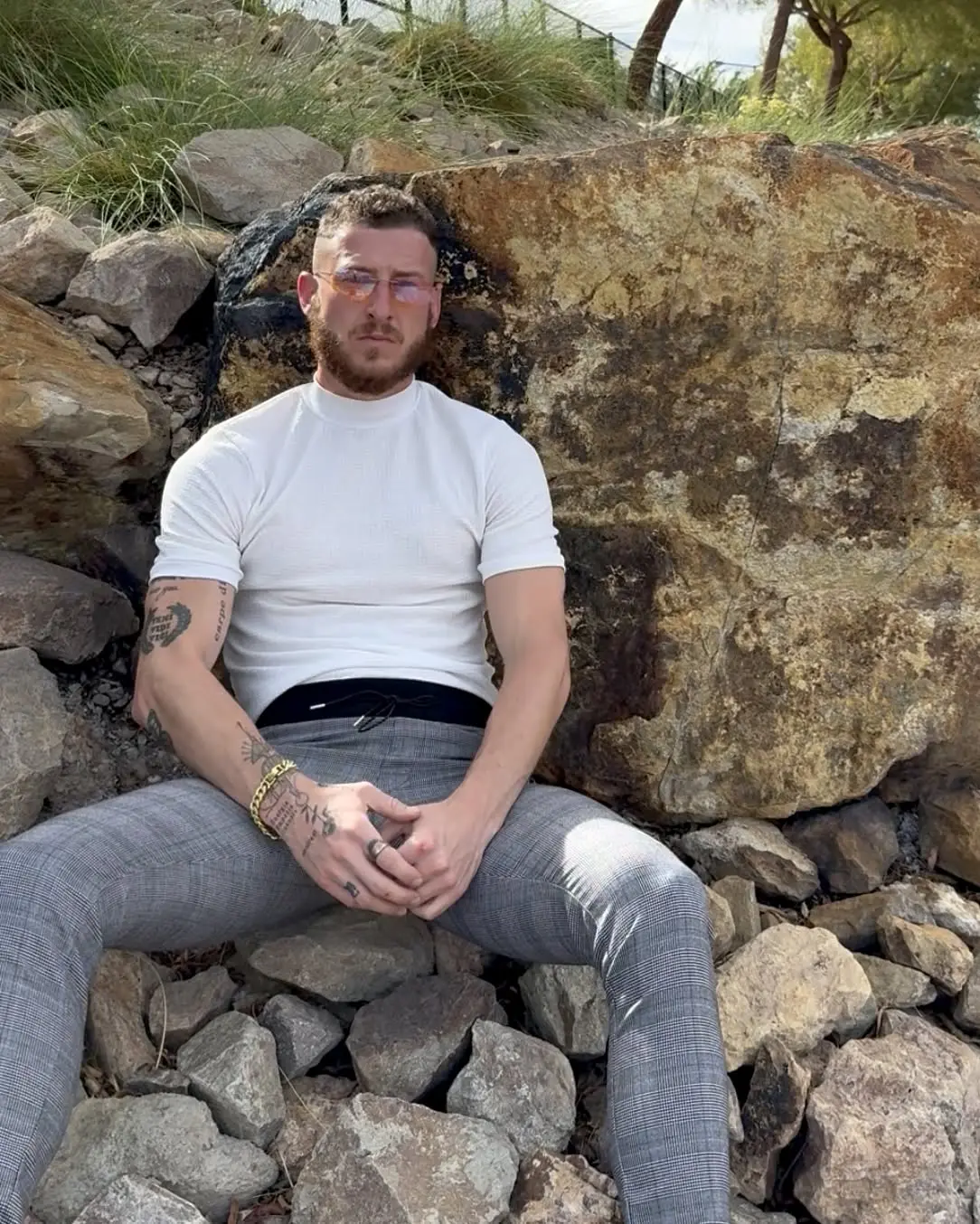 Michael Becker in a white shirt, seated on rocks outdoors